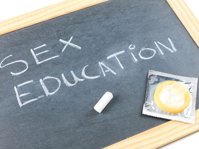 blackboard with chalked words 'sex education'. There is also a condom on the board.